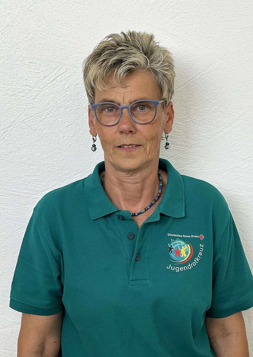 Eine Frau mit Brille. Sie trägt ein Shirt mit der Aufschrift "Jugendrotkreuz"